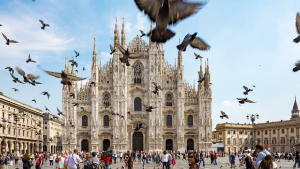The Milan Cathedral with flying birds during a sunny day in Milan