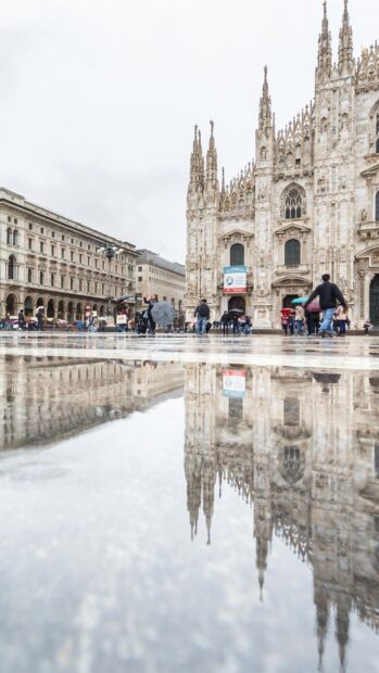 Milan reflection captures the iconic architecture of Milan with people walking nearby