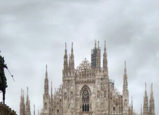 The famous Milan cathedral stands tall with busy tourists around the square