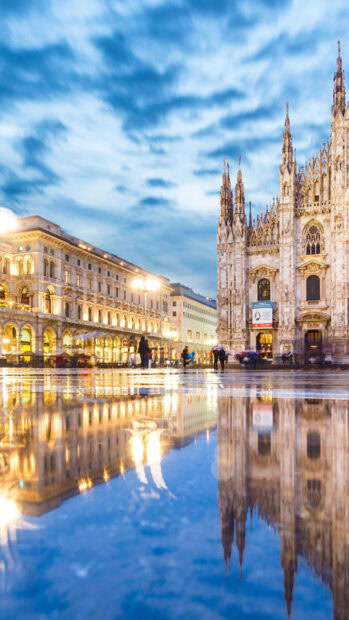 Milan architecture reflected in water with cloudy sky and people walking in the cityscape