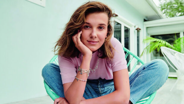 Millie Bobby Brown is sitting on a chair with a relaxed expression, HD Desktop Wallpaper