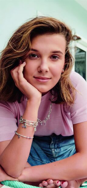 Millie Bobby Brown relaxes wearing a pink top and bracelets, HD Phone Wallpaper