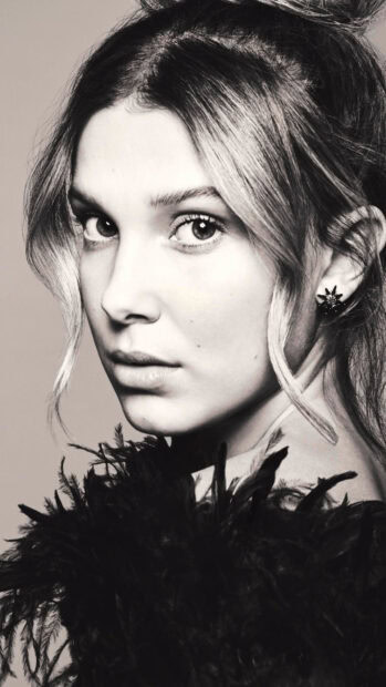 A close up portrait of Millie Bobby Brown with styled hair and detailed earrings, 2K Phone Wallpaper