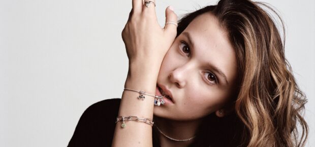 Millie Bobby Brown wears charmeled bracelets and looks thoughtfully at the camera, 2K Desktop Wallpaper
