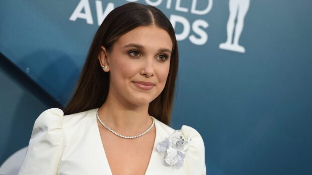 Millie Bobby Brown poses wearing a white dress with floral details and a diamond necklace, 2K Desktop Wallpaper