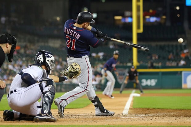 A Minnesota Twins player is swinging the bat at a fast moving baseball during a night game, 2K Desktop Wallpaper