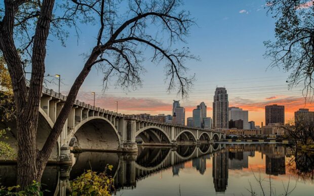 The Mississippi River shows a bridge and city skyline at sunset with calm reflective water, HD Desktop Wallpaper