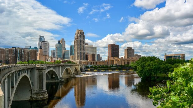 The Mississippi River flowing past a bridge and city skyline under a blue sky, 2K Desktop Wallpaper