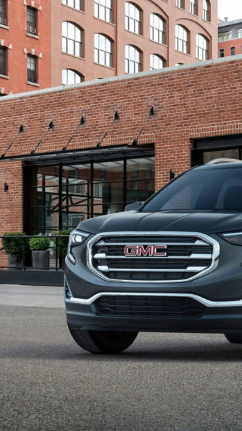 A modern GMC SUV is parked in front of a brick building on a city street, HD Mobile Wallpaper