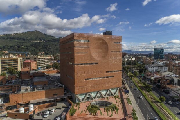 A large modern building stands prominently in Bogota with mountains in the background, HD Desktop Wallpaper