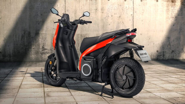 A black and orange scooter is parked on a tiled floor with a concrete wall background, 4K Desktop Wallpaper