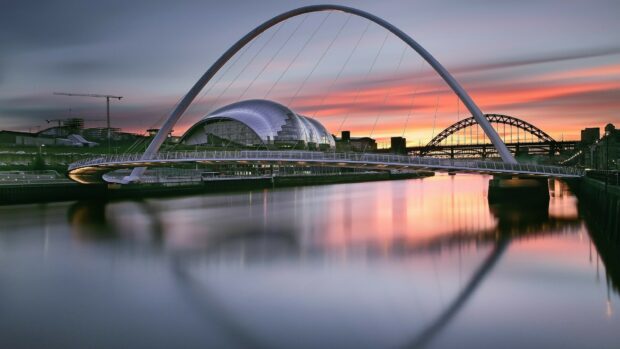 A modern curved bridge is reflected on the calm river during a colorful sunset in the United Kingdom, HD Desktop Wallpaper