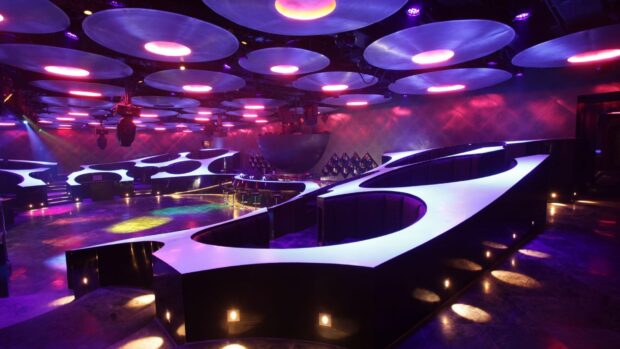 A modern nightclub interior illuminated with vibrant colored lights and unique seating, HD Desktop Wallpaper