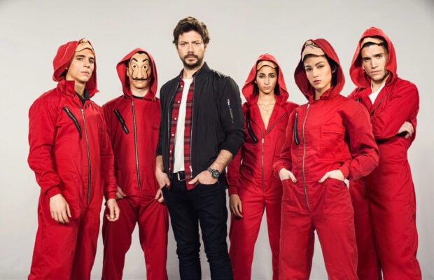 The Money Heist cast is standing confidently in their red jumpsuits and masks for a dramatic scene, 2K Desktop Wallpaper