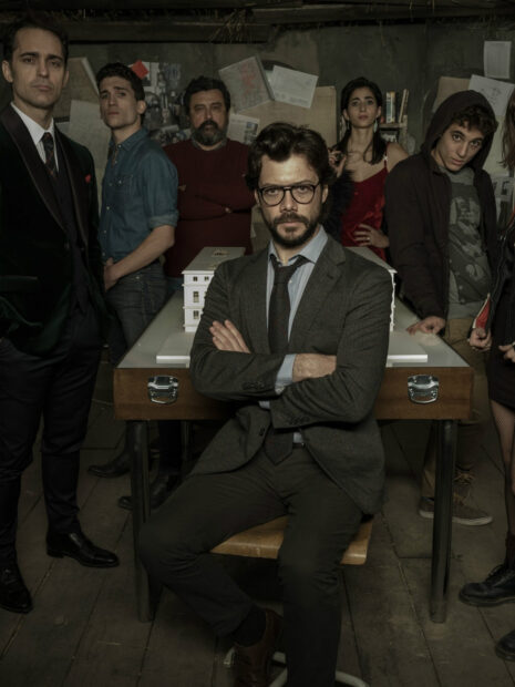 The Money Heist cast gathers around the table with serious expressions in a dimly lit room, HD Desktop Wallpaper