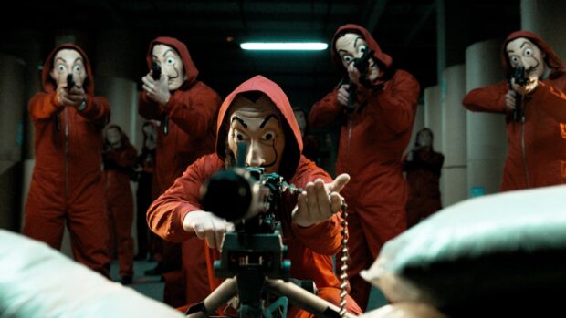The Money Heist crew wearing red jumpsuits and Salvador Dali masks aim guns inside a dark room, HD Desktop Wallpaper