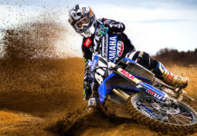 A motocross rider kicks up dirt while turning on the muddy track, 4K Desktop Wallpaper