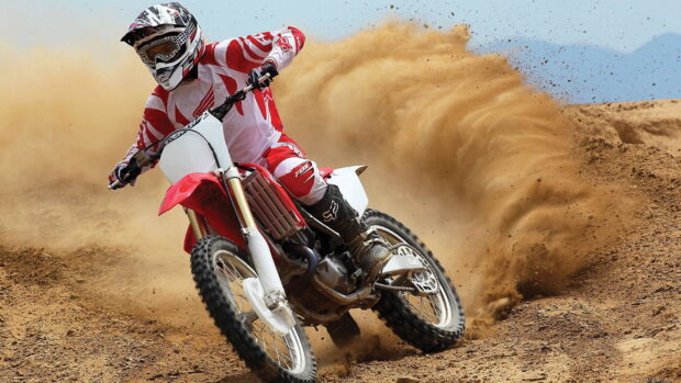 A motocross rider is drifting through a dirt track kicking up dust, 2K Desktop Wallpaper