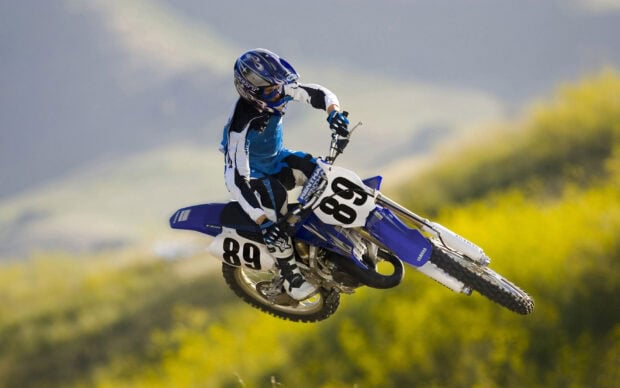 A motocross rider wearing blue gear jumps high on a Yamaha dirt bike during a race, HD Desktop Wallpaper