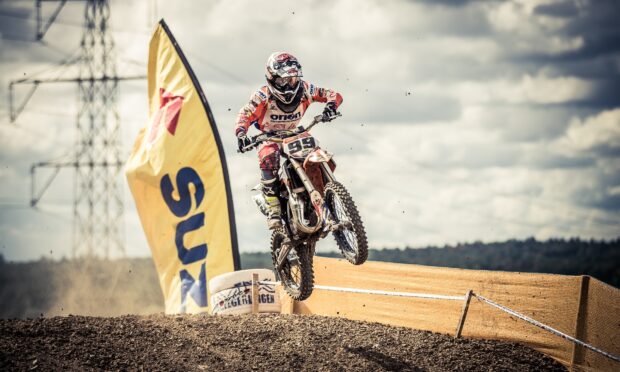 A motocross rider in full gear jumps over a dirt track during a race event, HD Desktop Wallpaper