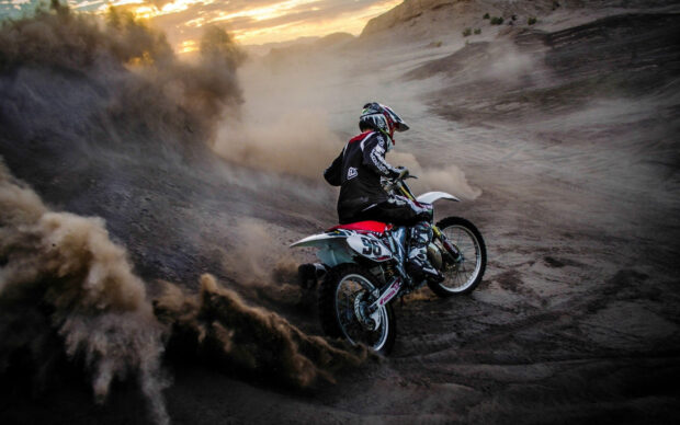 A motocross rider maneuvers through dirt with speed and skill during a sunset ride, 2K Desktop Wallpaper