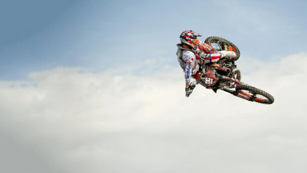 A motocross rider is captured performing an aerial stunt against a clear sky, 2K Desktop Wallpaper