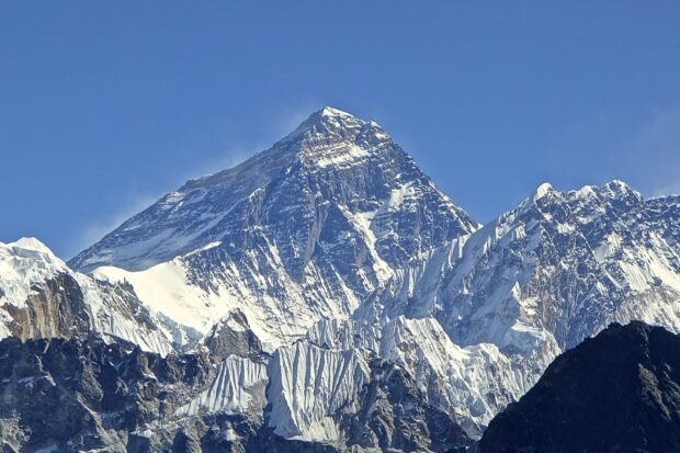 Snow covered Mount Everest stands tall under clear blue sky