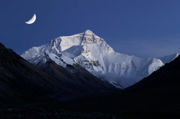 Snow covered Mount Everest under a crescent moon at twilight in high resolution