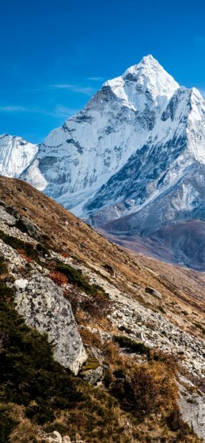 Snow covered mountain peak in Mount Everest with rocky terrain in the foreground