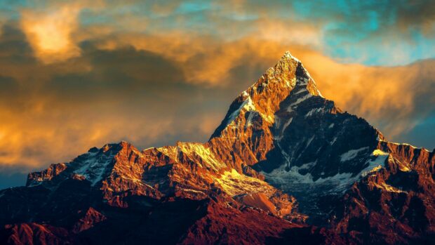 The Mount Everest peak glowing with golden sunlight under a dramatic sky