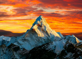 Snow covered Mount Everest peak illuminated by a vibrant sunset sky