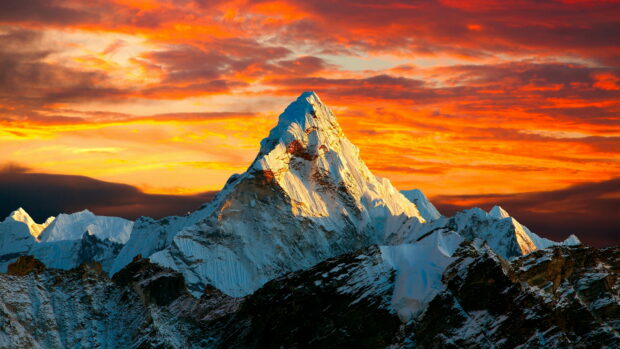 Snow covered Mount Everest peak illuminated by a vibrant sunset sky