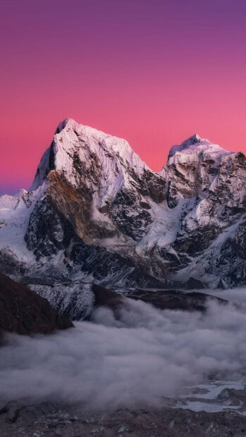 Snow covered Mount Everest peak standing tall above fog in the Himalayas