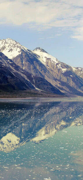 Snow covered mountain range of Mount Everest reflecting on icy water surface