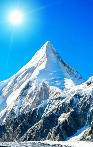 Snowy peak of Mount Everest under the bright sun and clear blue sky