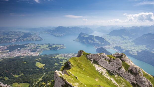 A scenic view of Mount Pilatus with green cliffs and a large lake in the background