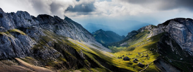 Rocky terrain of Mount Pilatus with green valleys and cloudy sky in the background