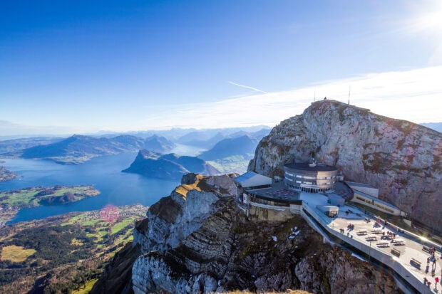 A scenic view of Mount Pilatus with rocky peaks and surrounding landscape under clear blue sky