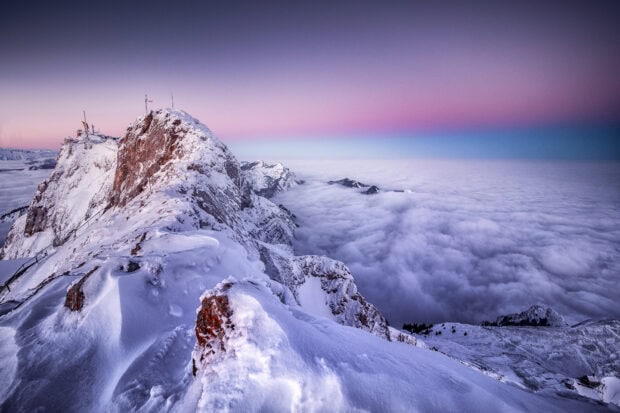 Snow covered peaks of Mount Pilatus overlooking a sea of clouds at sunrise
