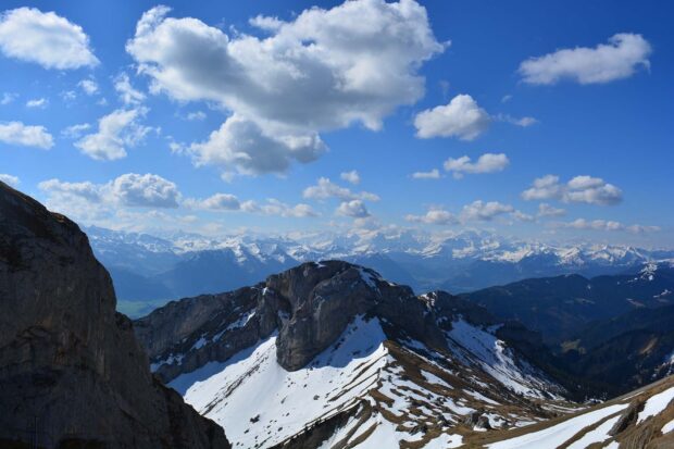 Snow covered rocky mountain peaks of Mount Pilatus under a bright blue sky with clouds