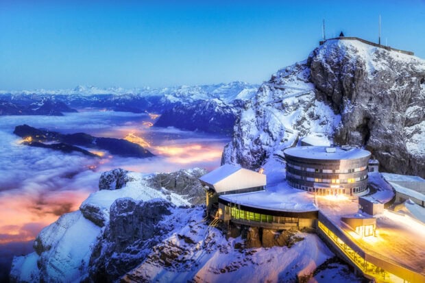 Snowy mountain landscape with Mount Pilatus and illuminated buildings at dusk