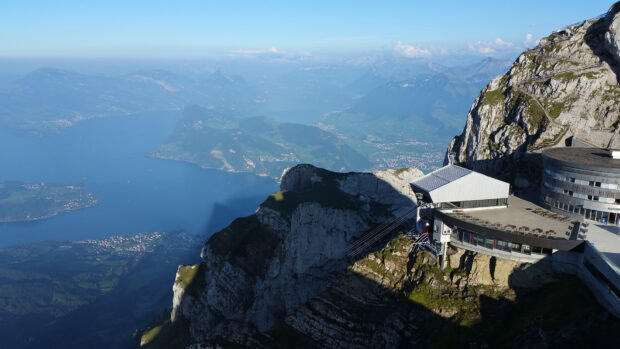A scenic view of Mount Pilatus with rugged cliffs and a lake in the background visible from the mountain top station