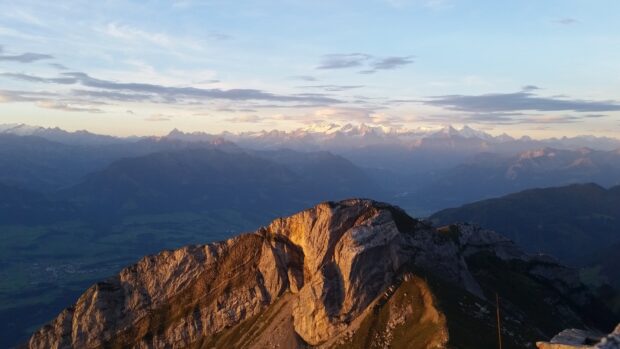 Rocky landscape of Mount Pilatus during sunset with clear sky and distant mountains in view