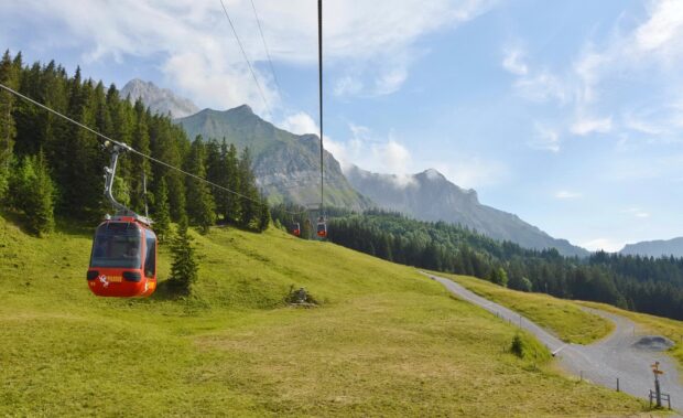 Red cable cars ascending Mount Pilatus with alpine forest and blue sky background