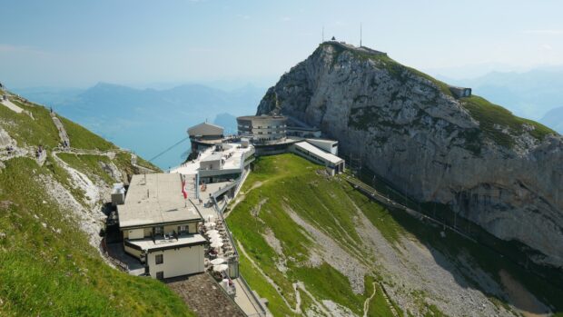 A scenic view of Mount Pilatus with buildings and green slopes under clear blue sky