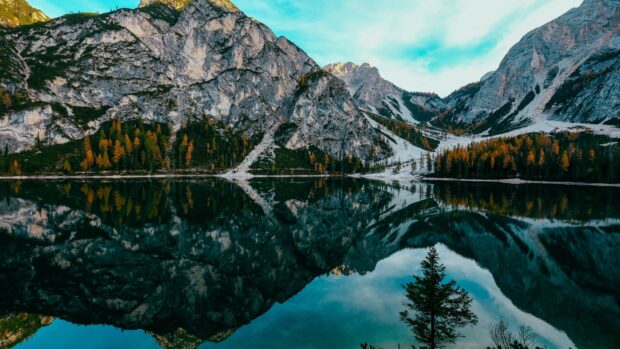 A mountain lake reflects rocky peaks and colorful trees under a blue sky, 4K Desktop Wallpaper
