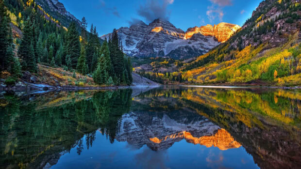 A calm mountain lake reflects colorful trees and peaks during autumn, 2K Desktop Wallpaper