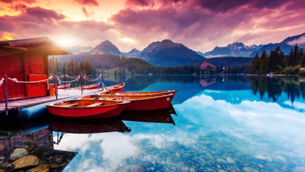 A calm mountain lake with red boats docked and a vibrant sky, 4K Desktop Wallpaper