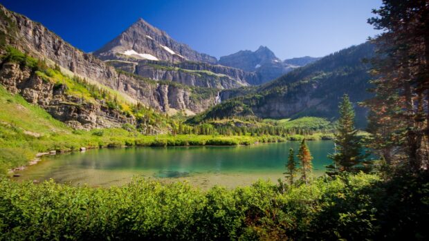 A tranquil mountain lake surrounded by lush greenery and rocky cliffs, 2K Desktop Wallpaper