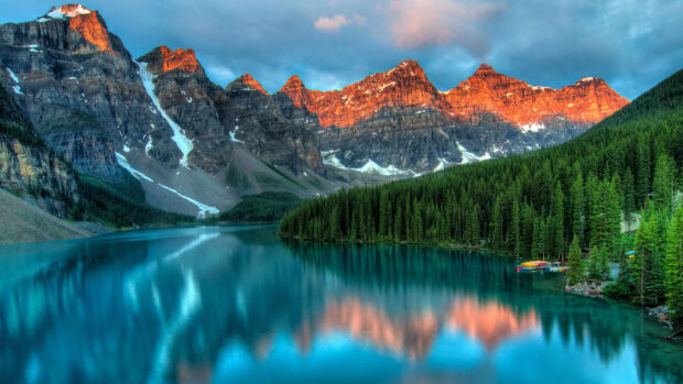 A serene mountain lake reflects the glowing peaks and tall pine trees during sunset, 4K Desktop Wallpaper